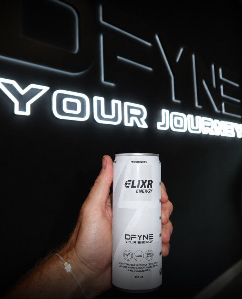 Hand holding an Elixr Energy drink can with 'DFYNE' branding in front of a dark background with illuminated text.
